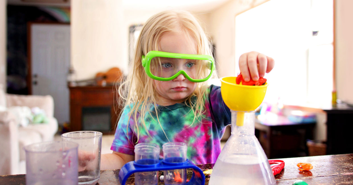 A little girl playing with a science toy.