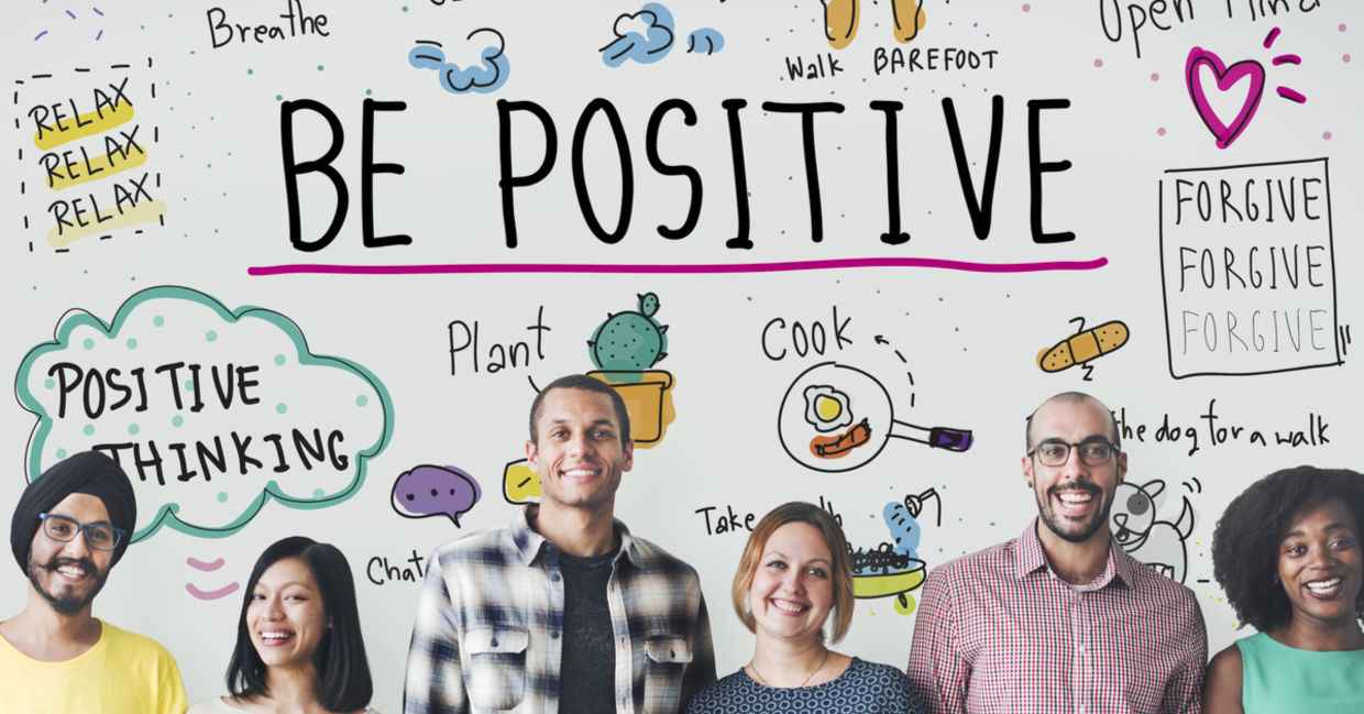 A group stands in front of a sign depicting positive thinking with images of ideas to feel good.