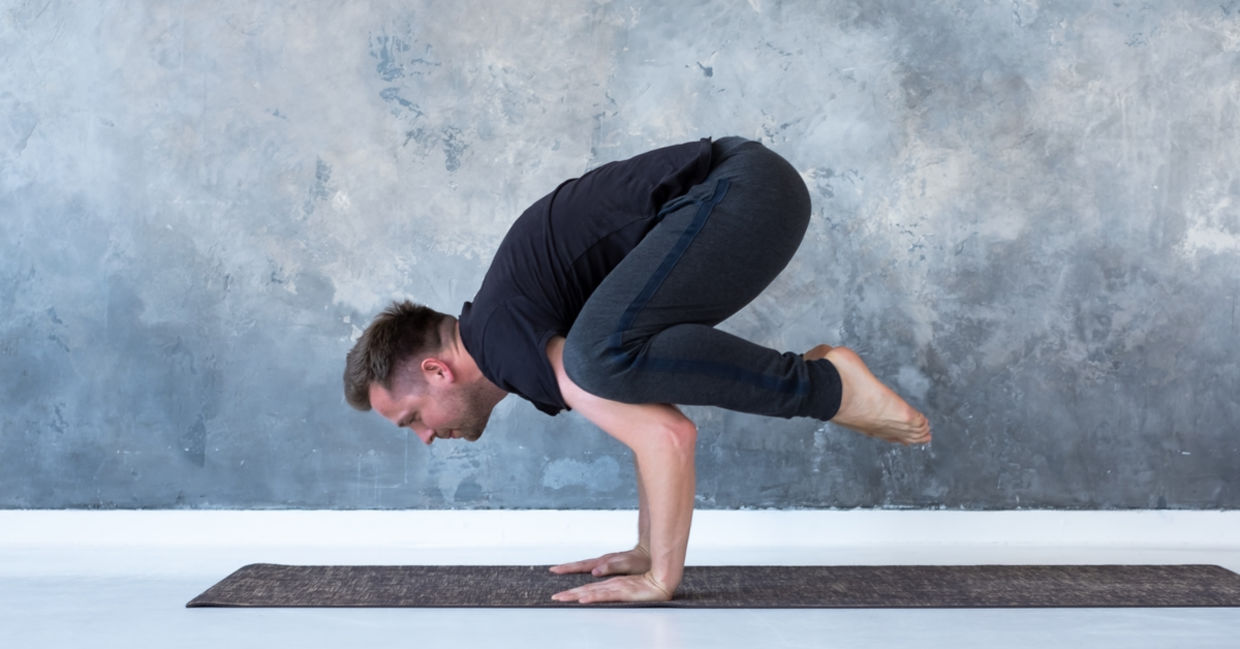 Man performing the crow yoga pose.