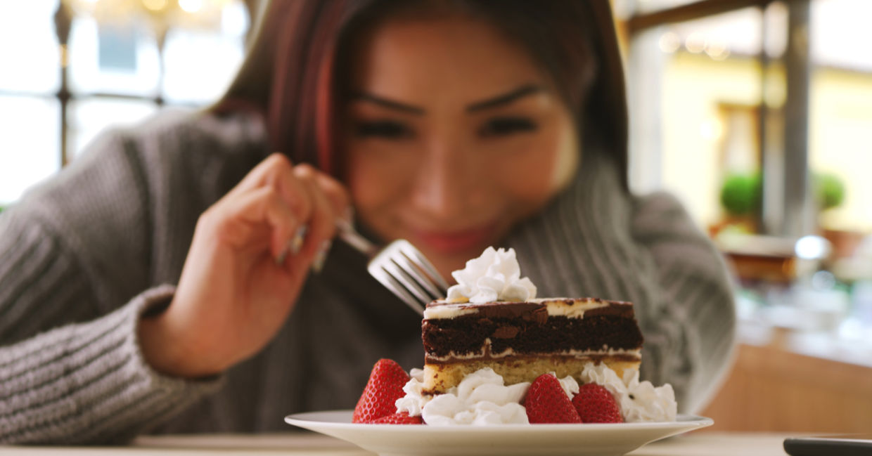 A woman happily indulges in a fancy dessert.