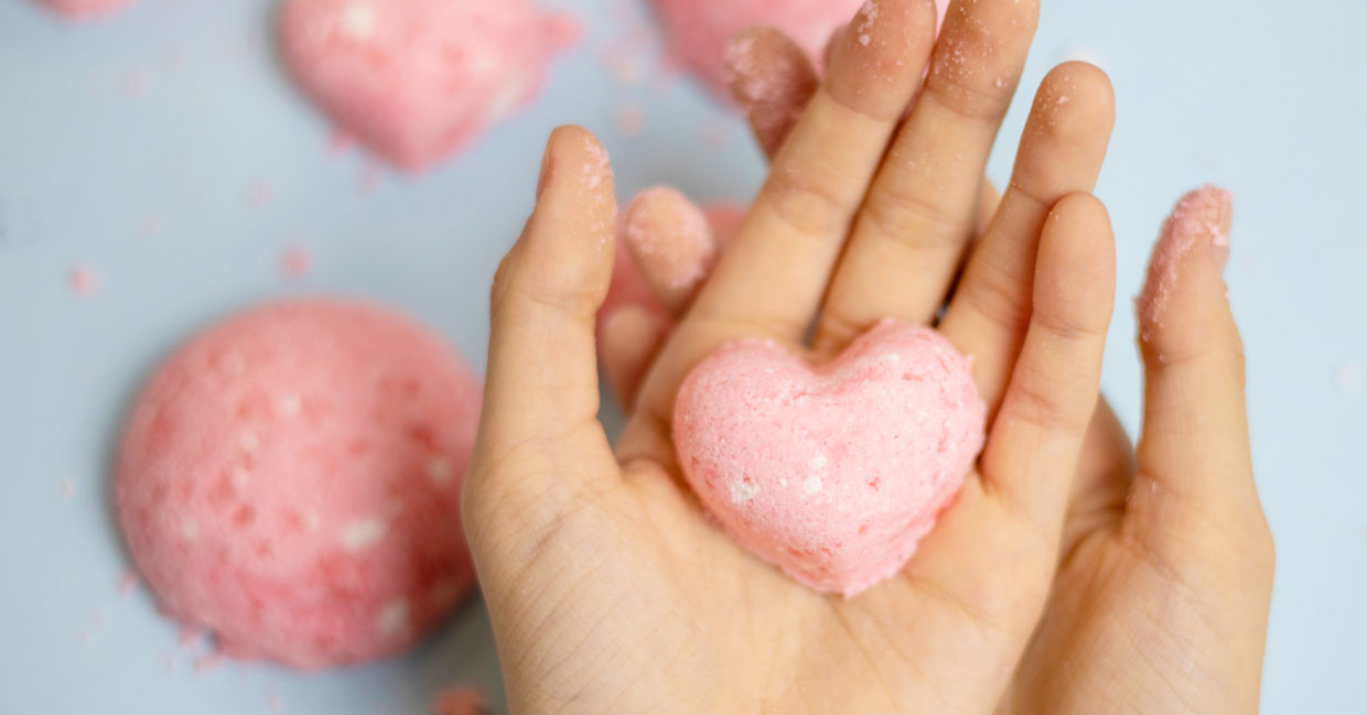 A child makes a pink bath bomb in the shape of a heart.