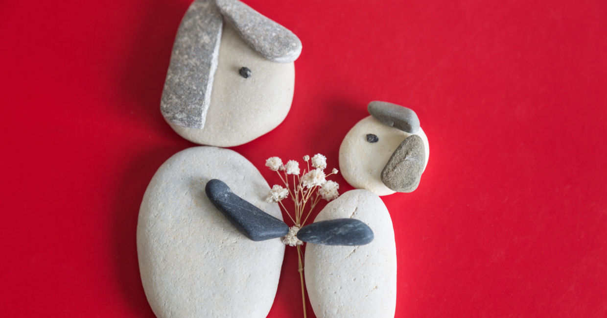 Pebble art shows a mother and child holding hands.