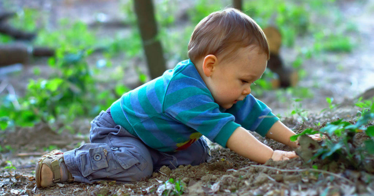 A baby plays in nature