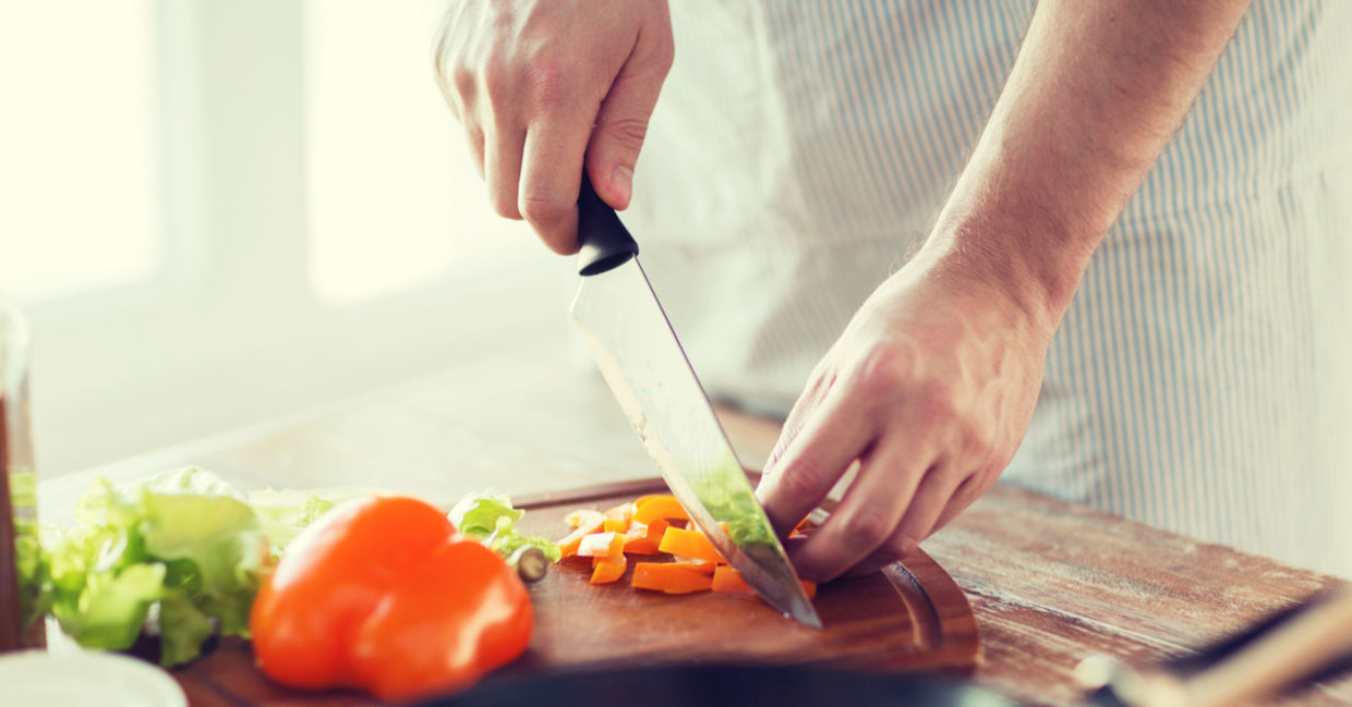 A person chopping vegetables on a wooden cutting board.