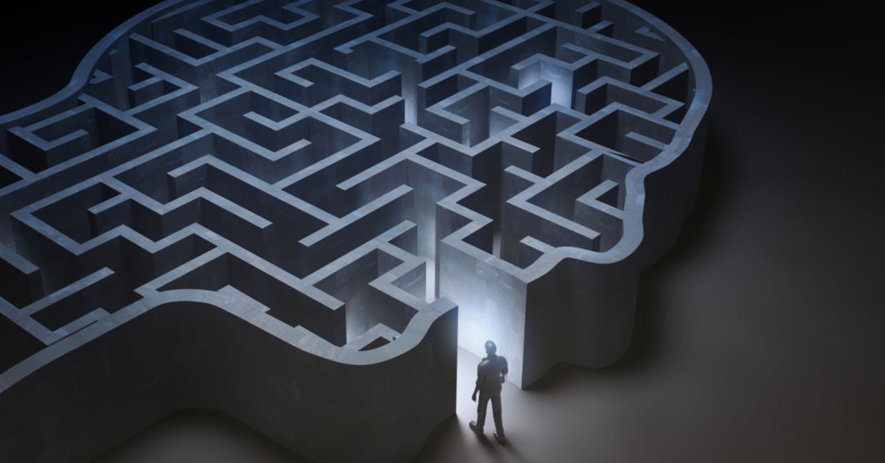A dreamy image of a man entering a maze that is in the shape of a human head.