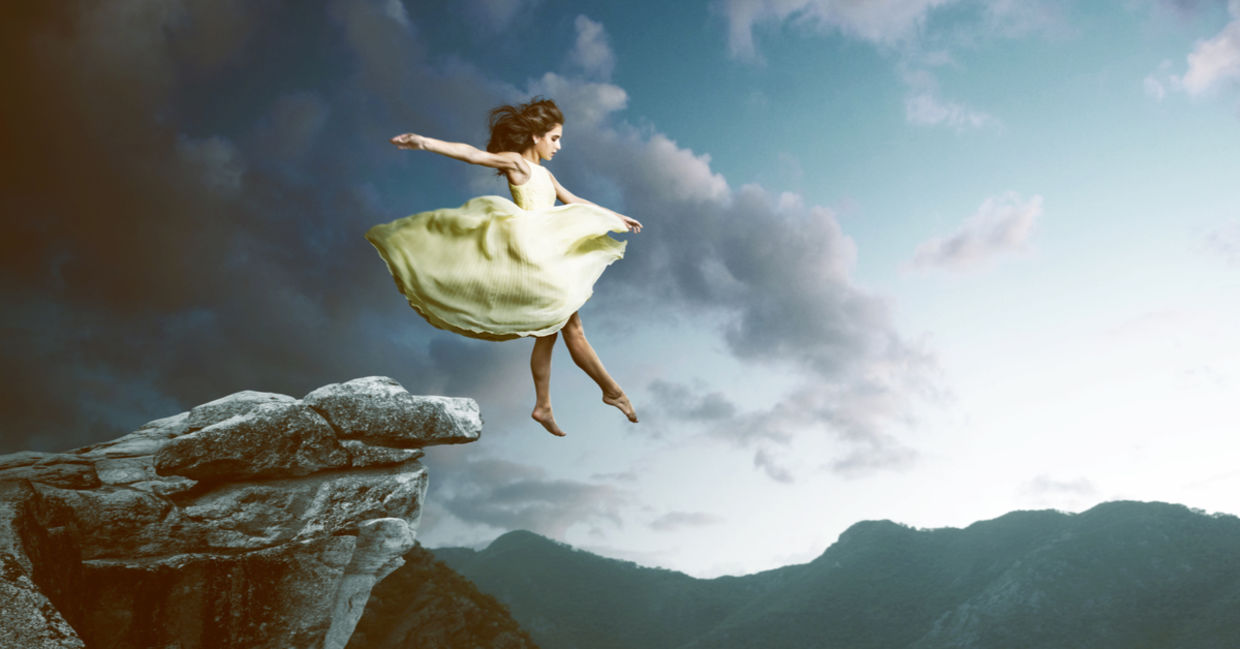 Dreamy image of a woman in a billowy dress floating off a high cliff.