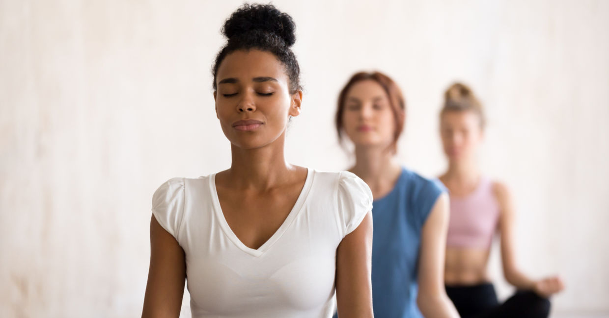 Women of diverse backgrounds meditate together.