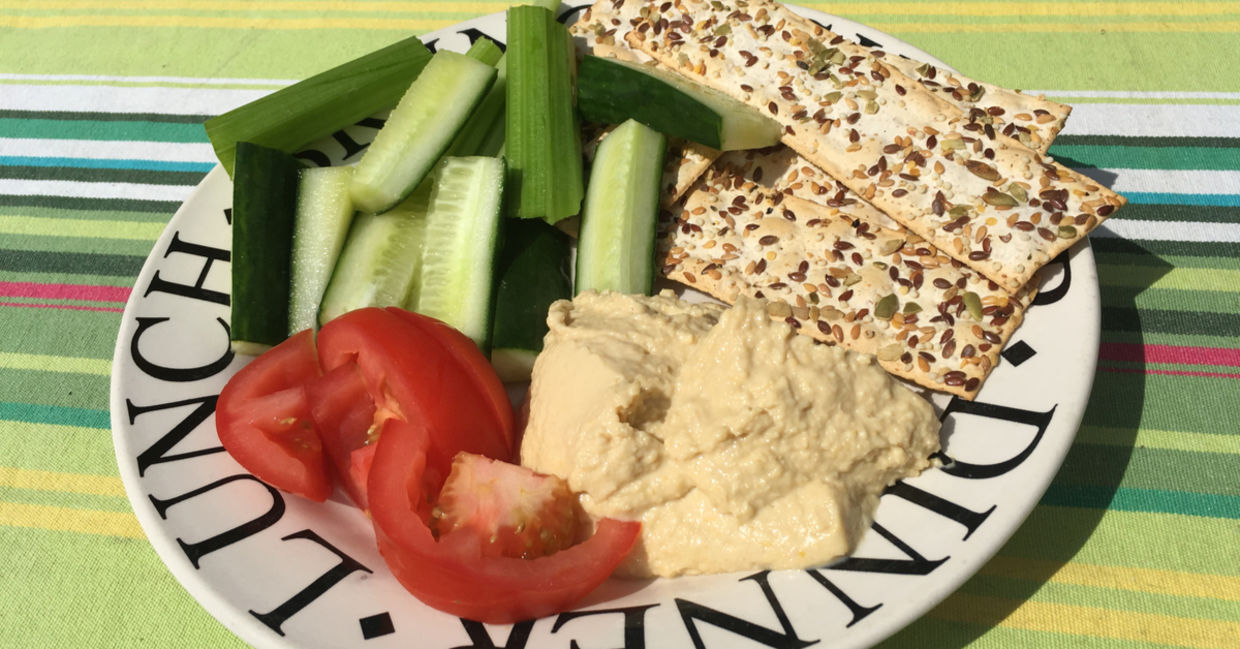 Healthy plate of hummus, crackers and sliced vegetables.