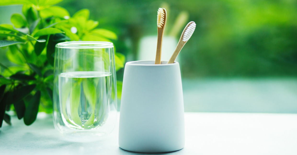 Bamboo toothbrushes in a cup and glass with water