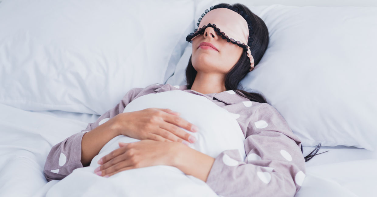 A woman wearing an eye mask is sleeping.
