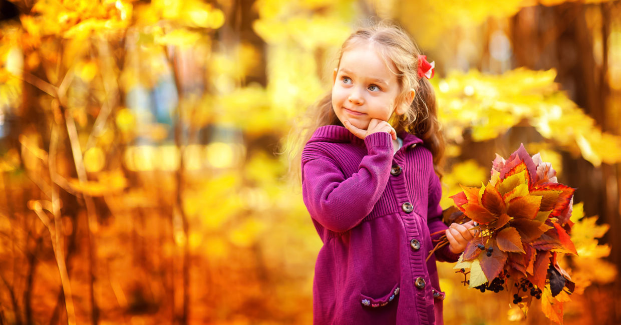 Happy little girl in autumn maple orange leaves