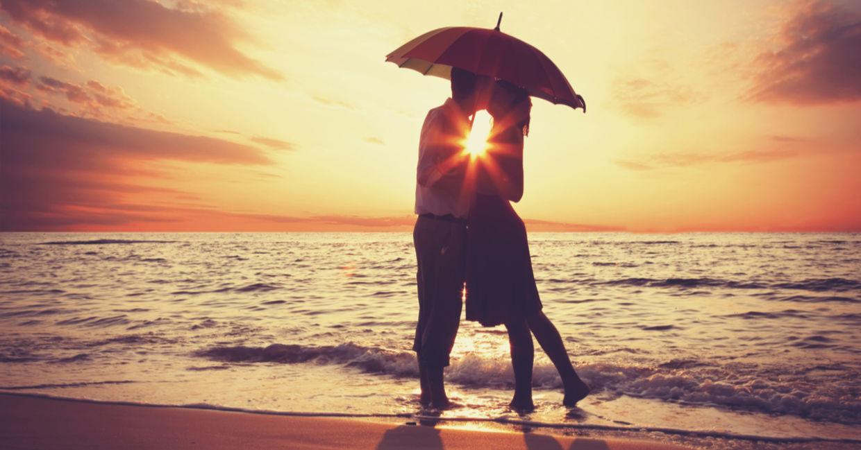Couple kissing under an umbrella.