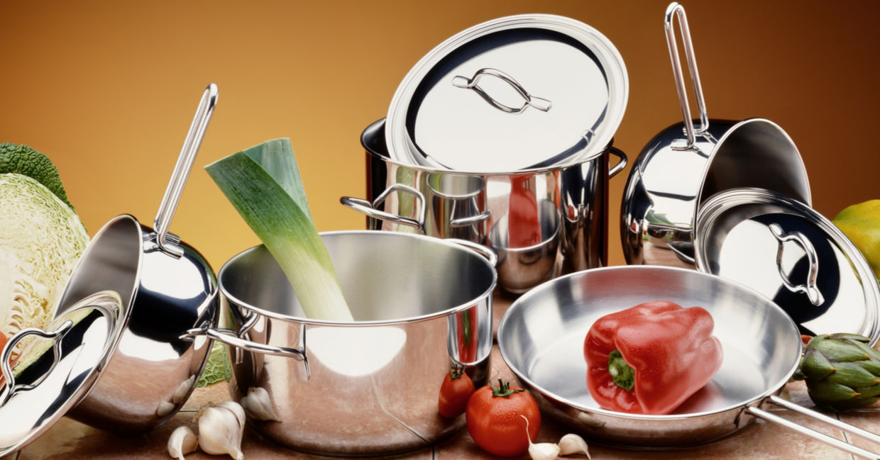A selection of stainless steel pots and pans with healthy, raw ingredients.