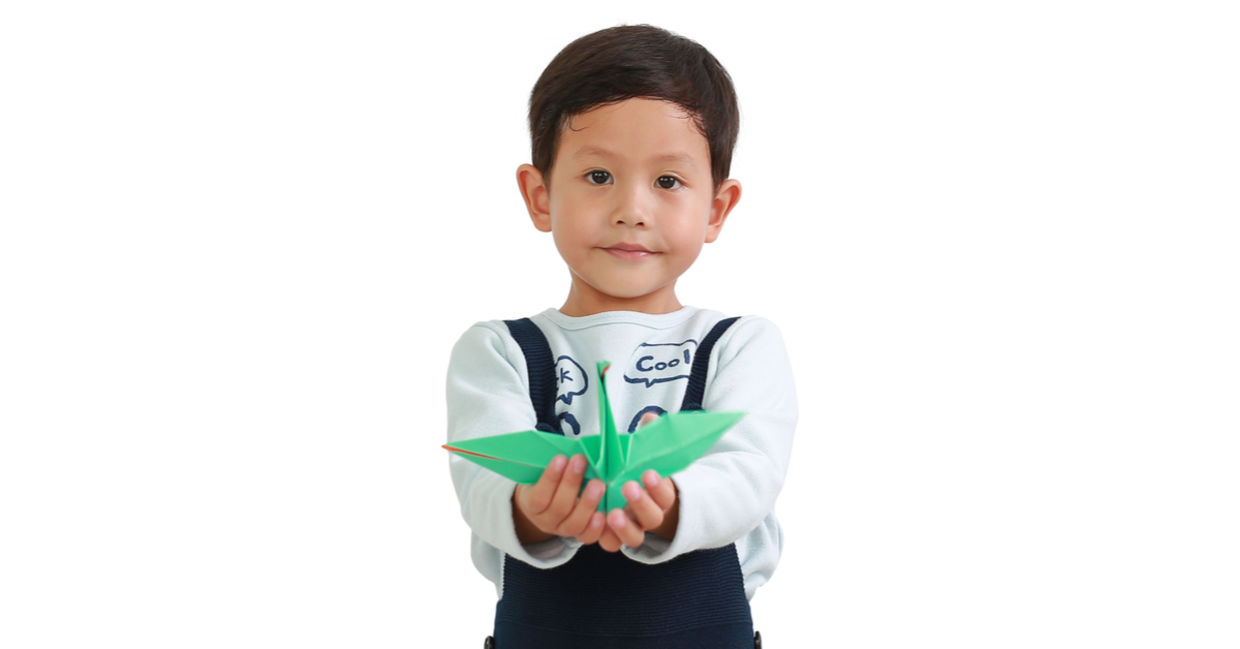 A little boy holds an origami bird.