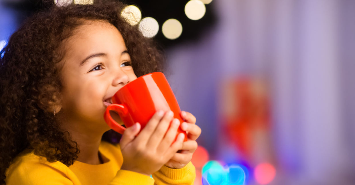 Young girl staying warm by drinking a hot cocoa.