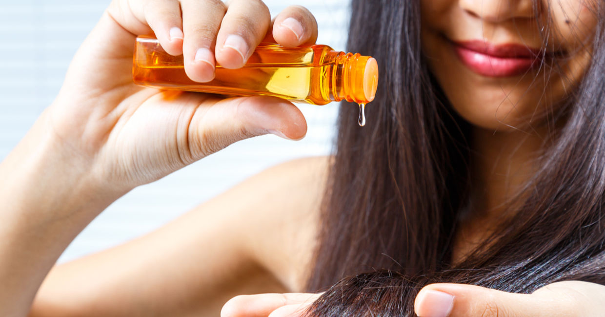 A woman treats her split ends with drops of healing and nourishing vitamin E oil.