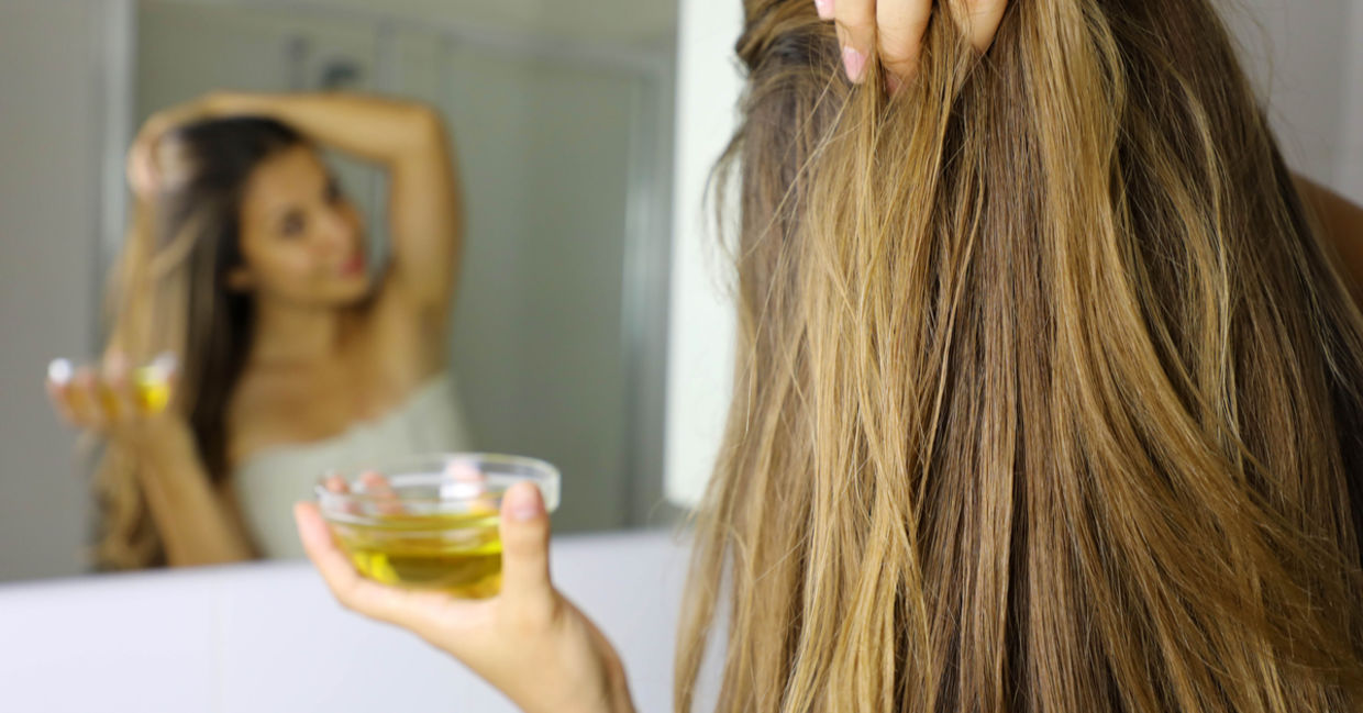 To revitalize her hair, a woman rubs vitamin E and coconut oil into her scalp.