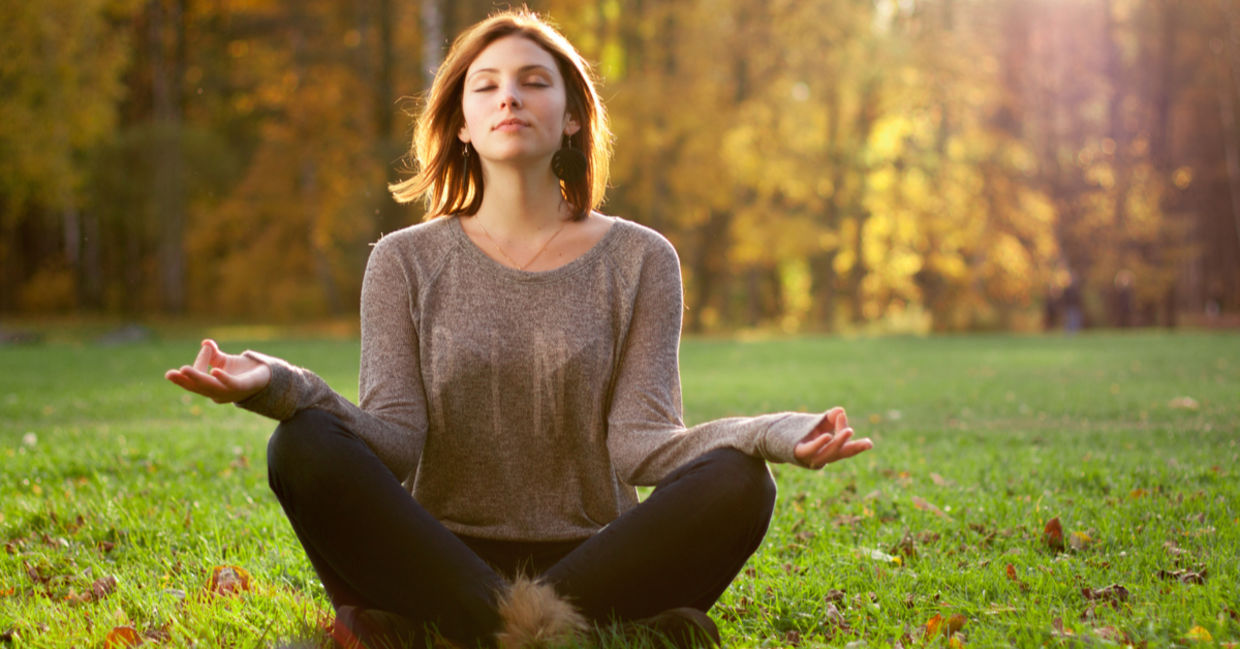 Young woman meditating near trees