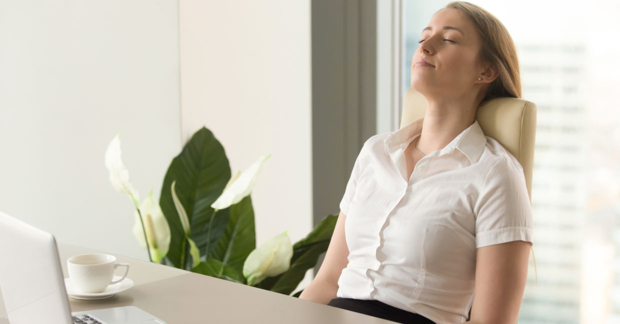A woman sits comfortably at her desk and practices mindfulness.