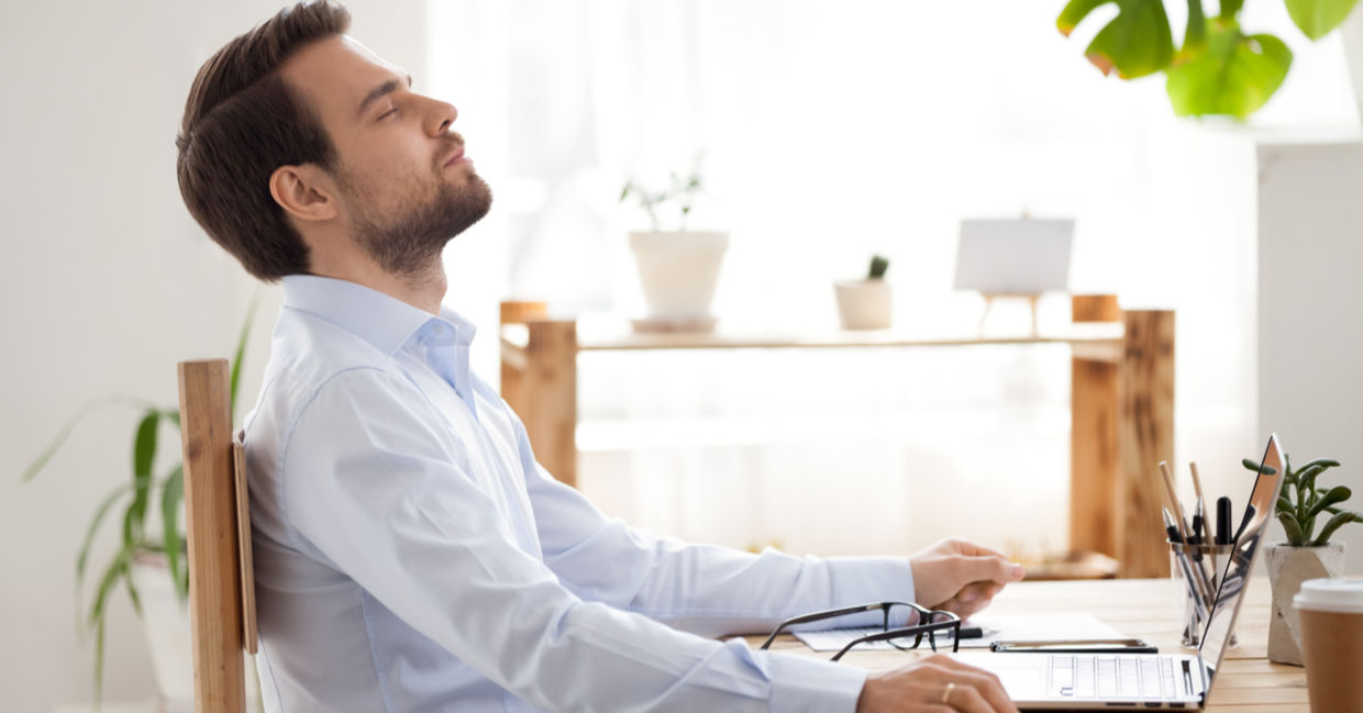 A man takes a break from work and practices mindfulness at his work.