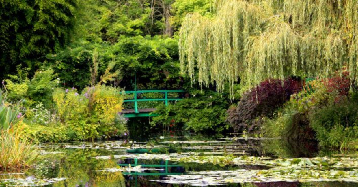 The iconic green Japanese bridge reflecting in the water lily pond in Claude Monet's Garden of Giverny, Normandy, France