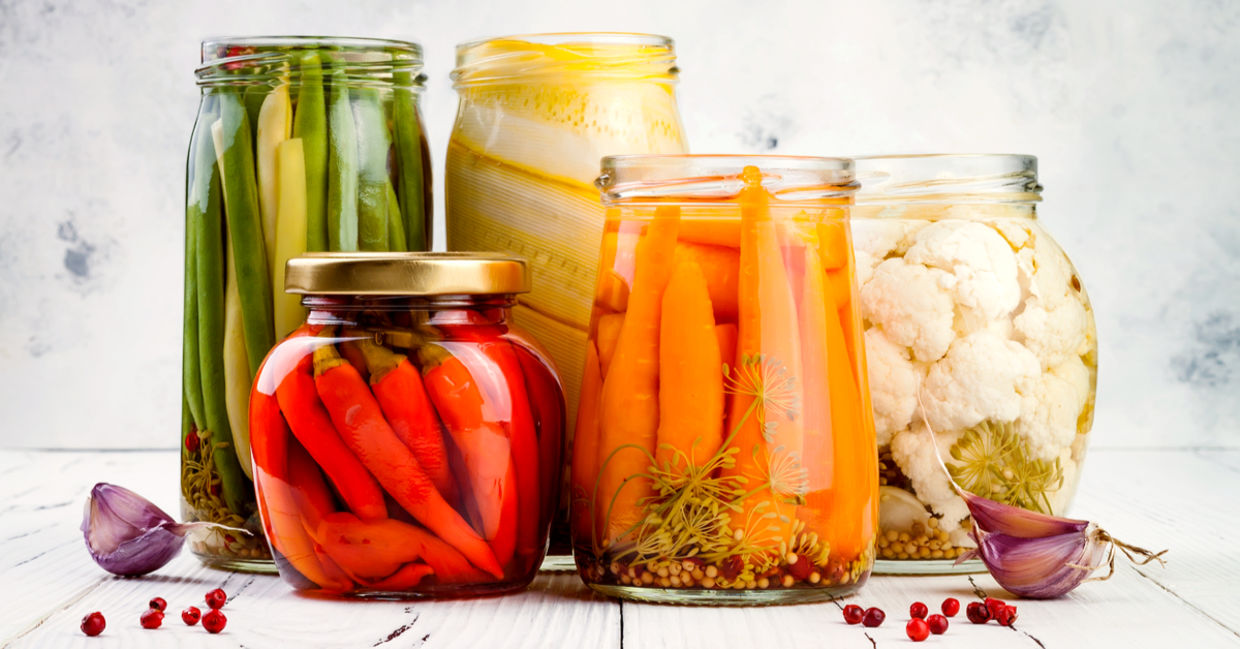An appetizing selection of marinated pickled vegetables in glass jars.