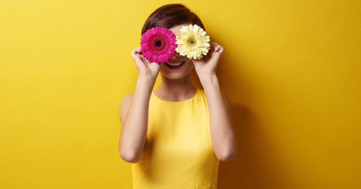 Happy woman covering her eyes with flowers