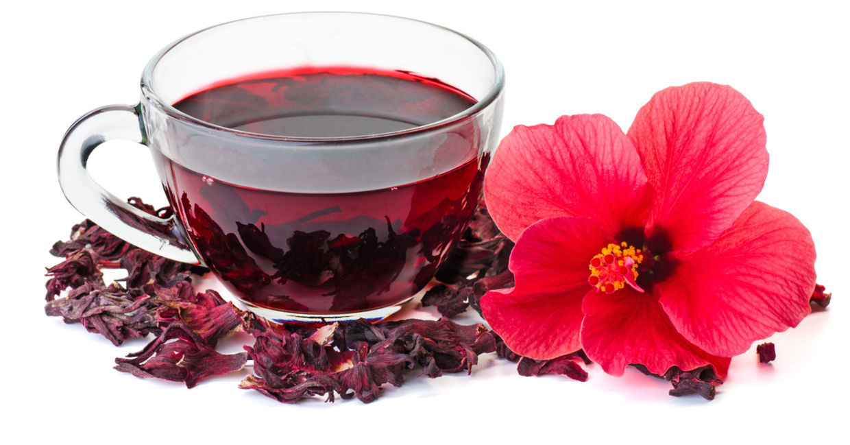 A hibiscus flower beside a cup of healthy hibiscus tea.