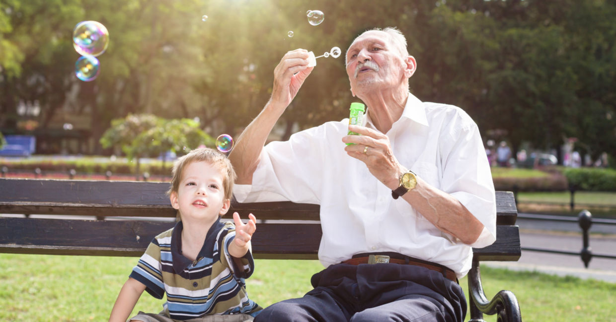 A young boy and an old man blowing bubbles.