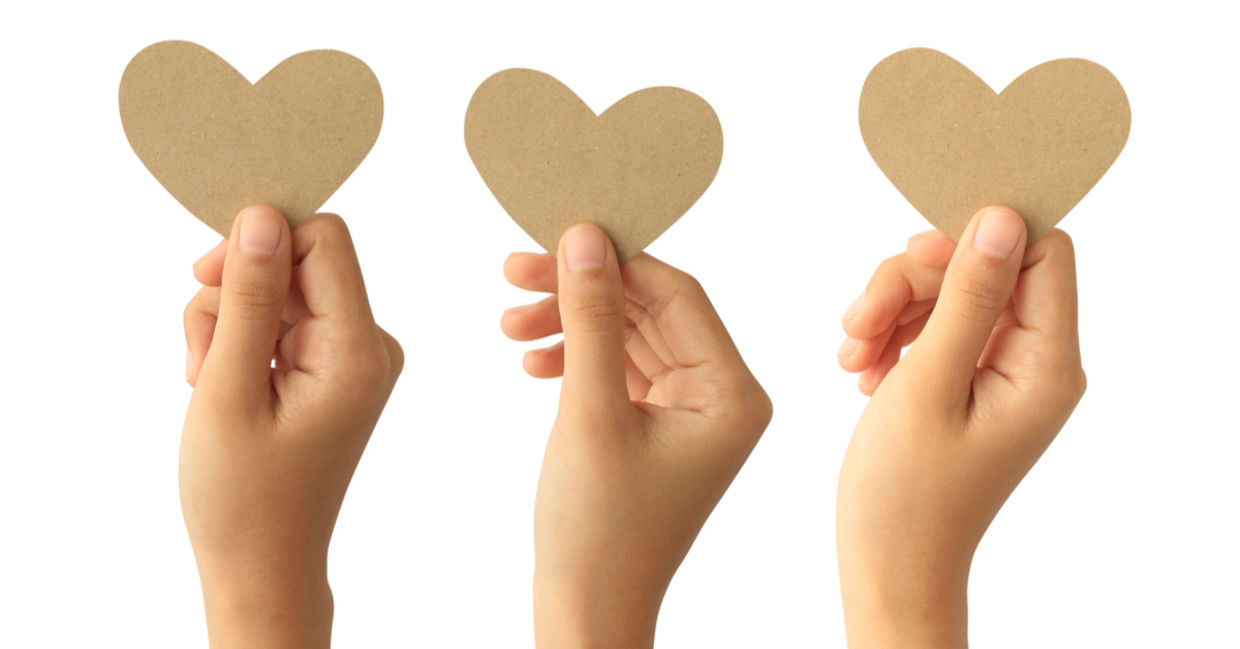 Hands holding paper hearts to signify kindness
