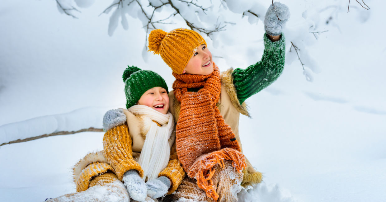 Two young girls happily play in the snow.