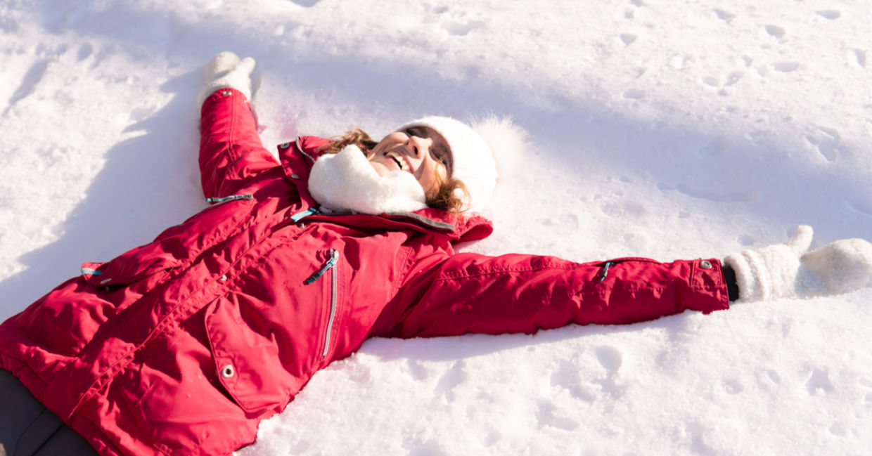 A woman lies in the snow, her body forming a sitzmark.
