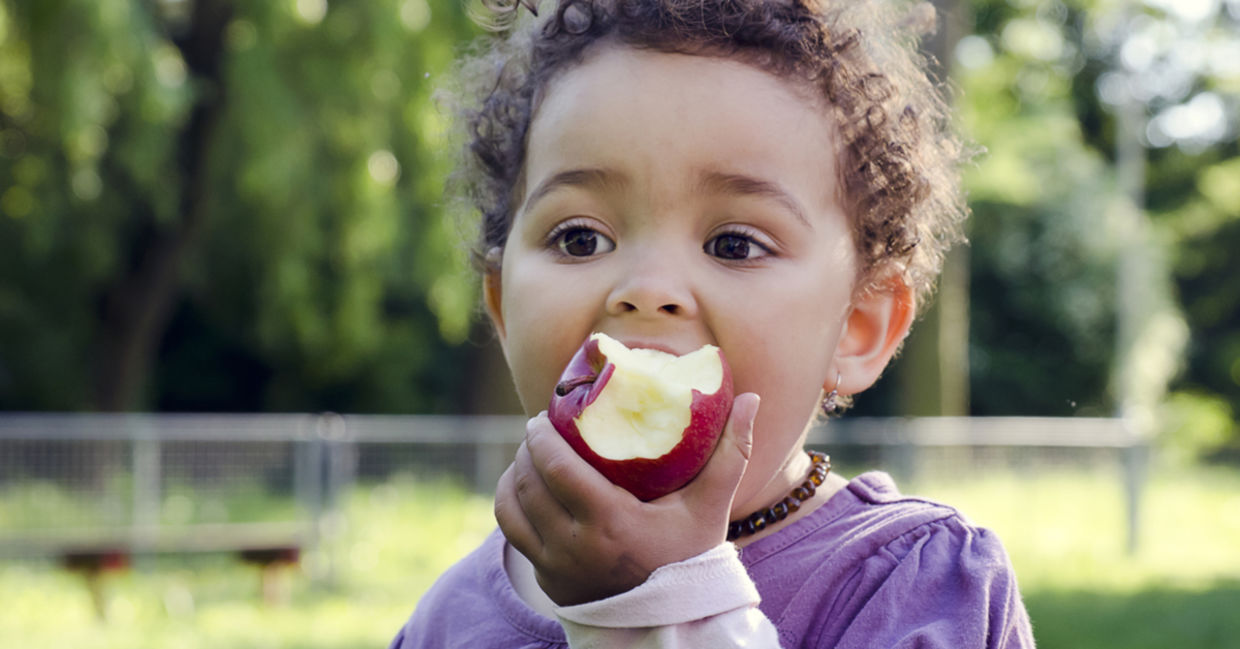 A young girl is enjoying eating an apple.