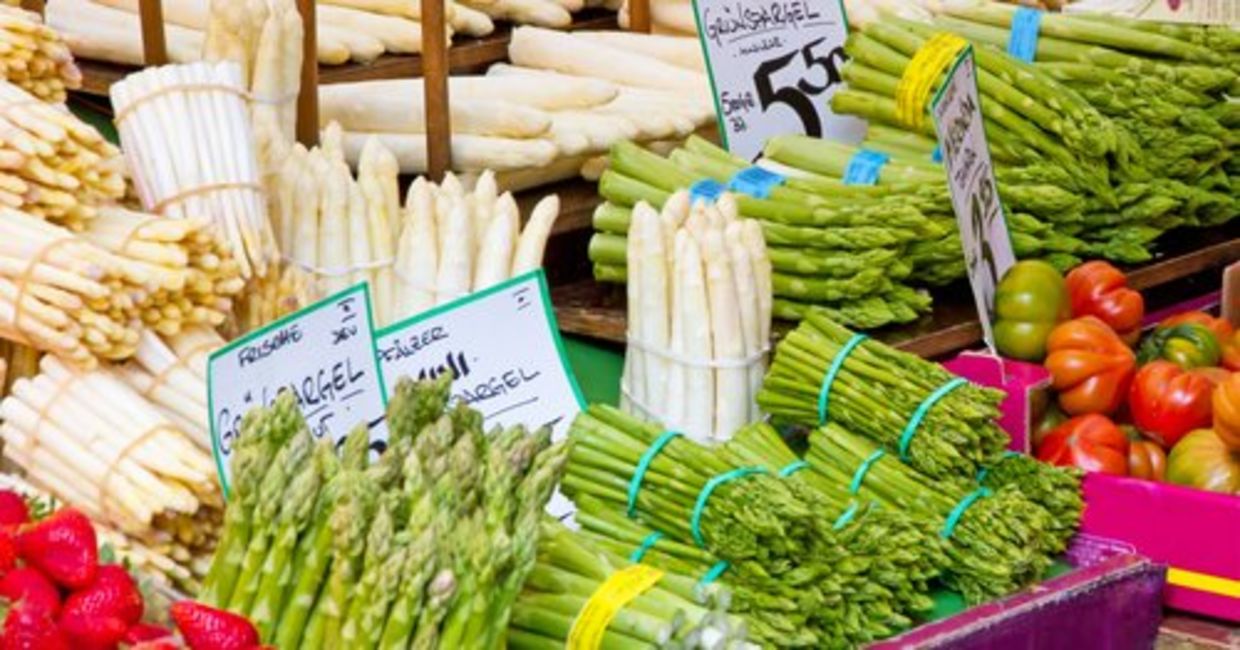 Green and white asparagus are displayed at a farmers’ market.