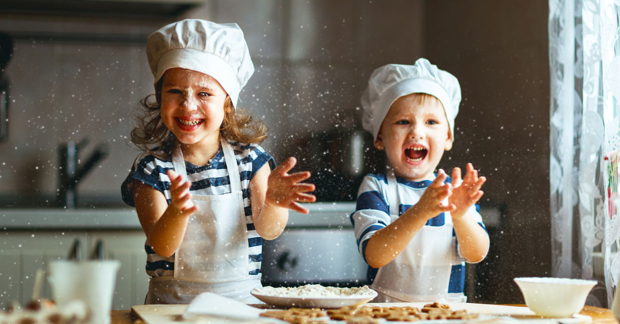 Happy kids enjoying baking cookies in their home kitchen.