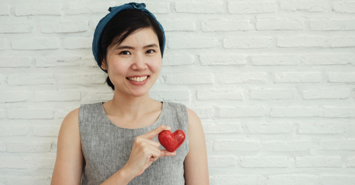 A kind woman holding a red heart.