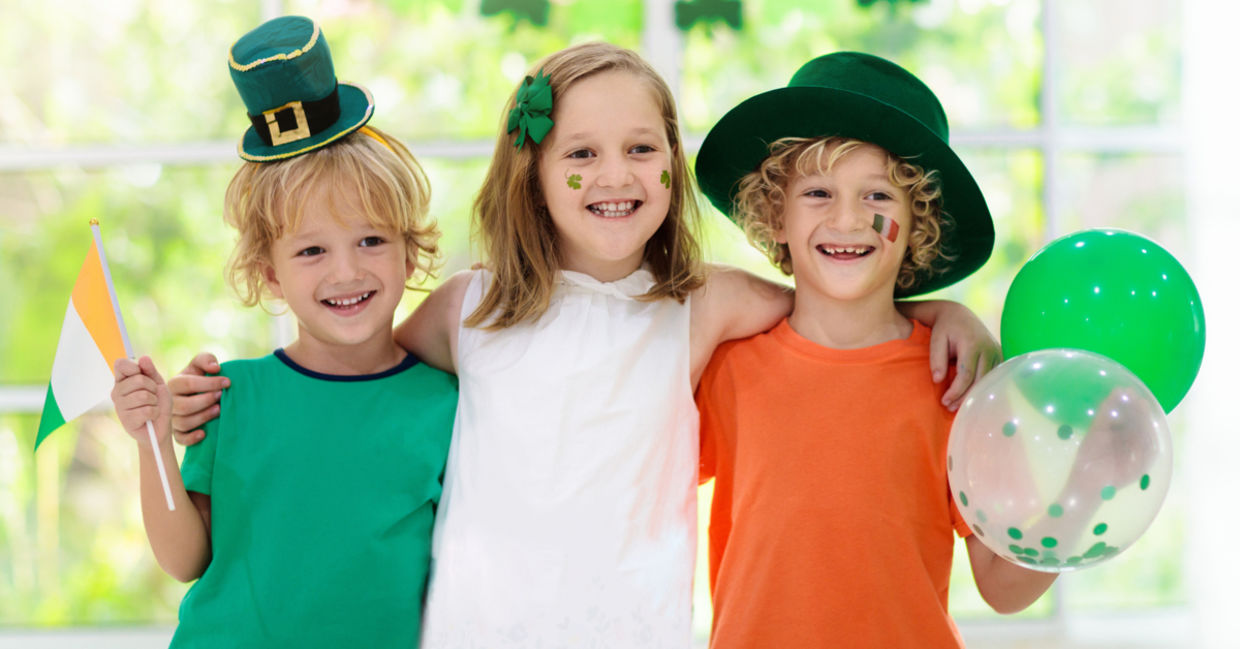 Children celebrate St. Patrick's Day by wearing a leprechaun hat and waving an Irish flag.