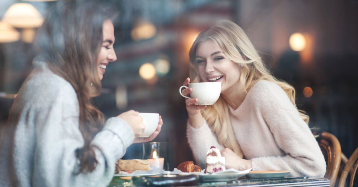 Two girlfriends connect over coffee for a gezellig day at a cafe.