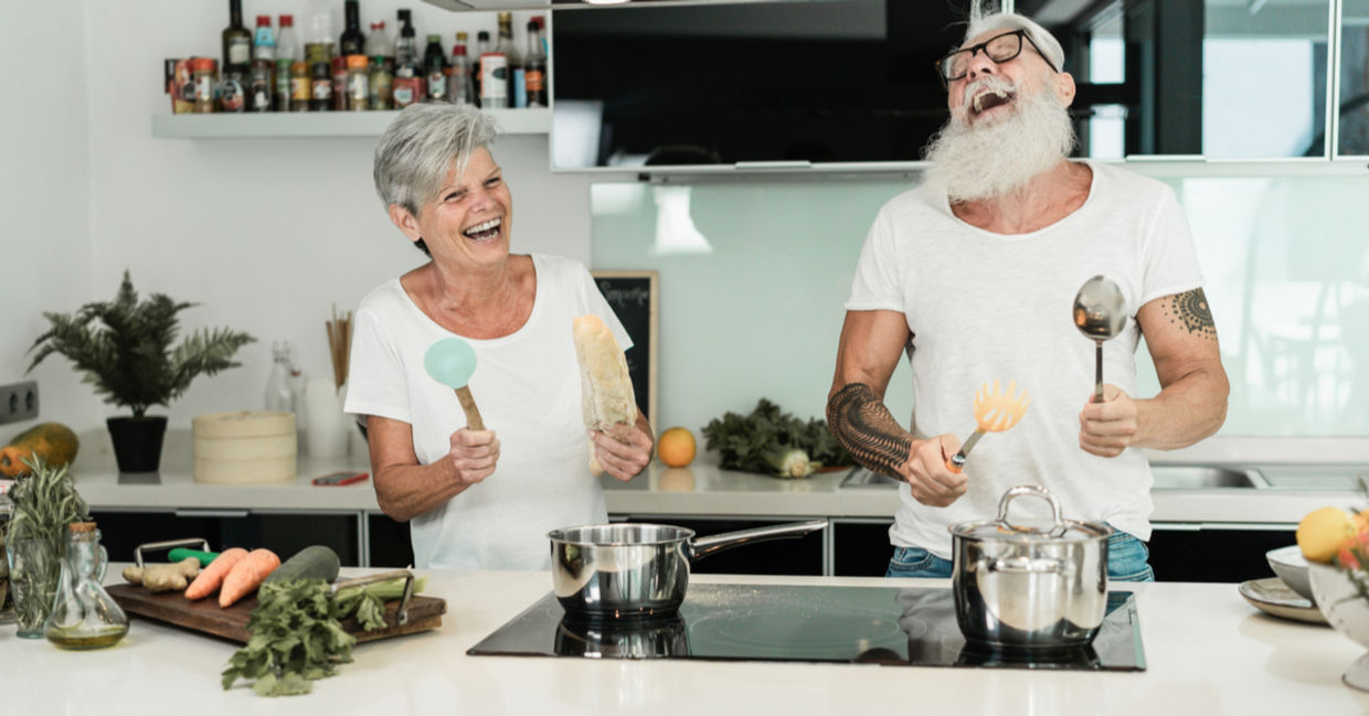 Senior couple dancing while cooking together.