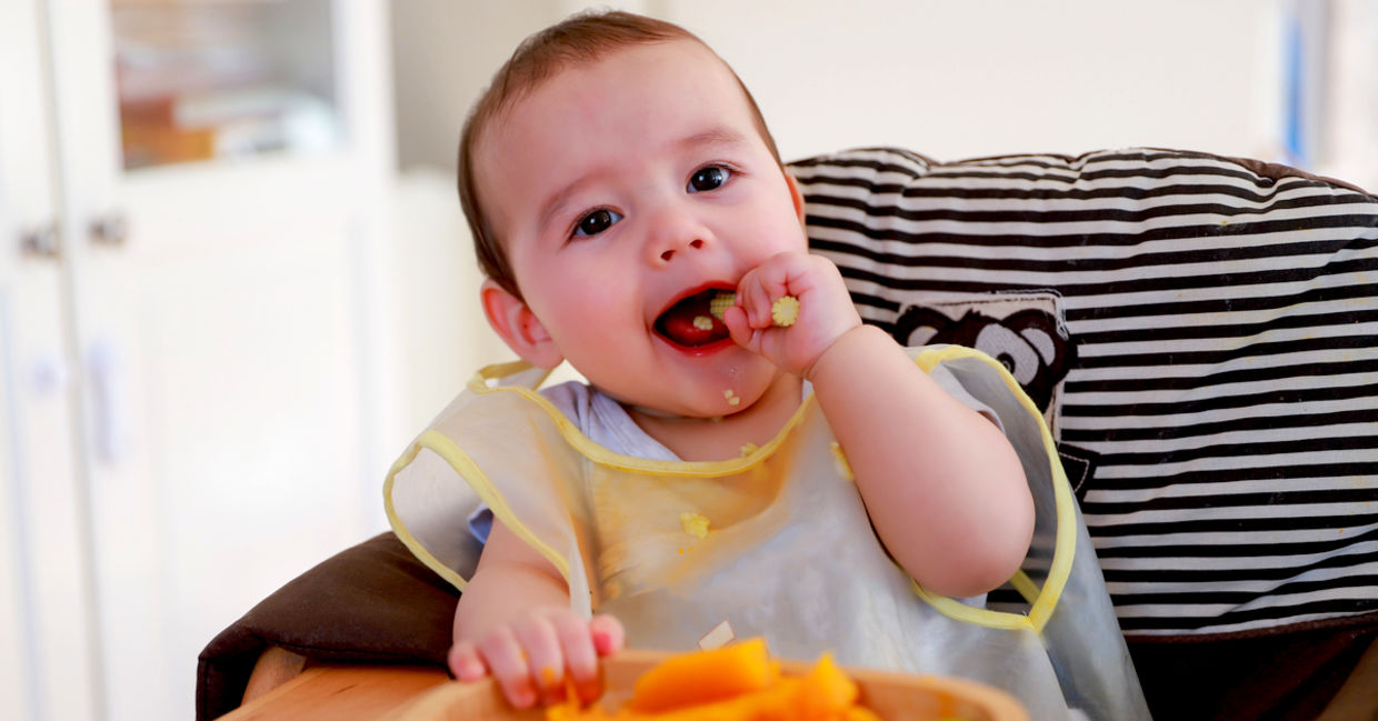 Cute baby eating cooked vegetables.
