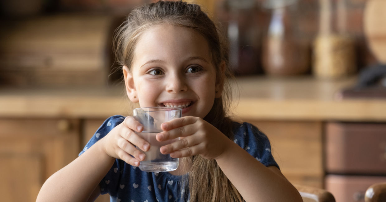 Girl enjoying quenching her thirst with clean mineral water from a glass.