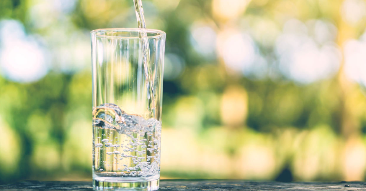 Pouring fresh water into a drinking glass on a sunlit morning.