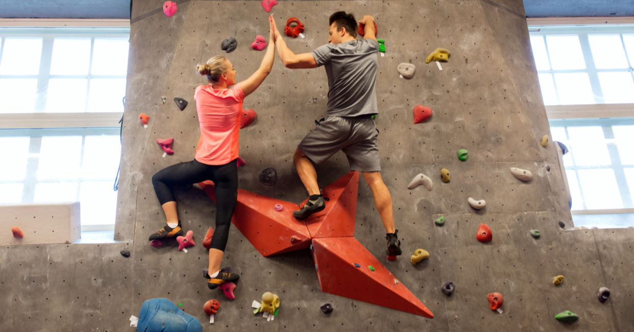 Indoor rock climbers making a high five gesture.