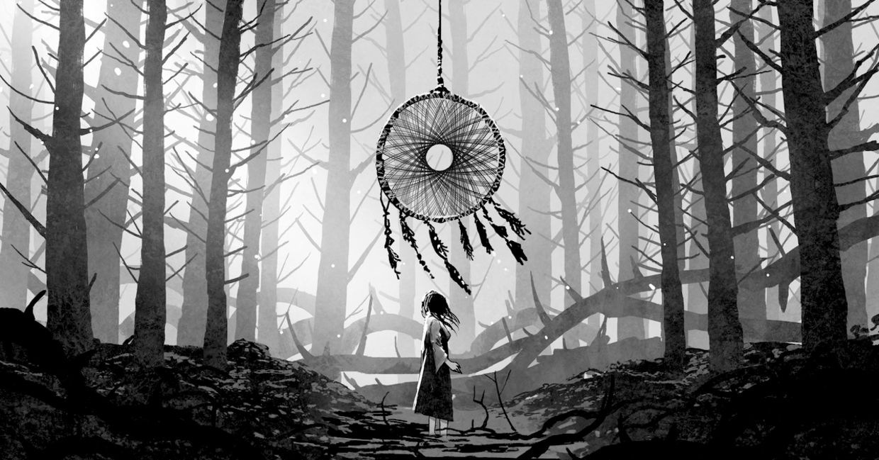 Woman standing and looking at a dreamcatcher hanging from the trees in a forest.