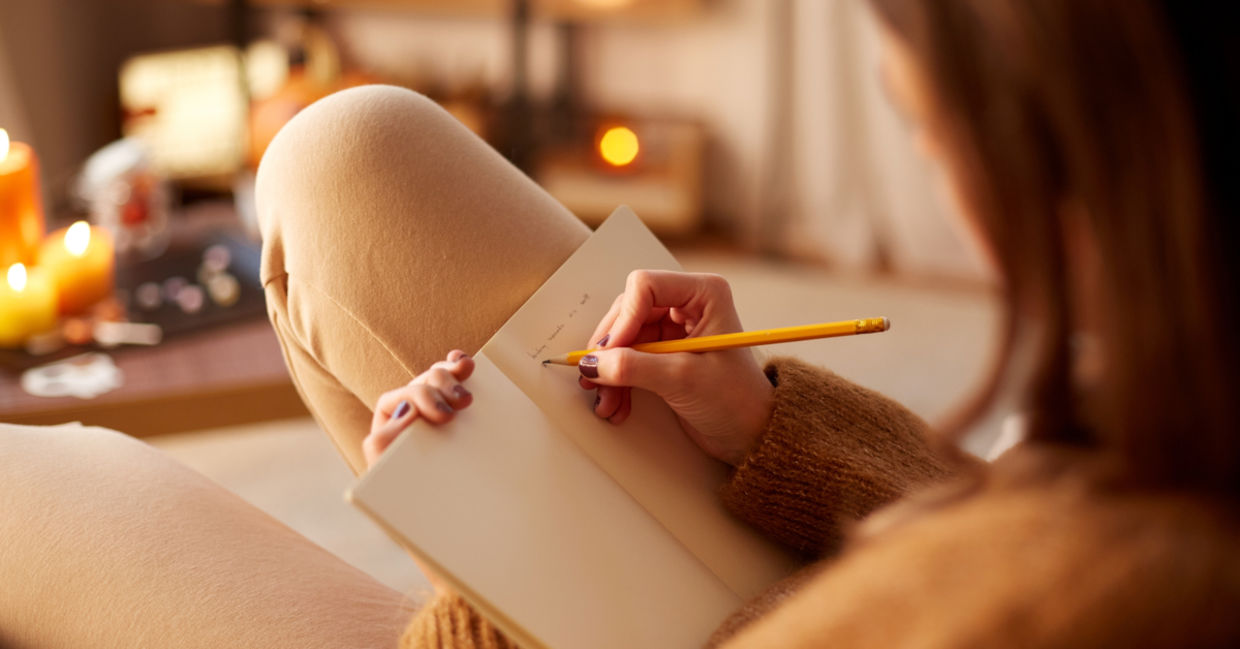 Woman writing in diary while relaxing in her cozy home.