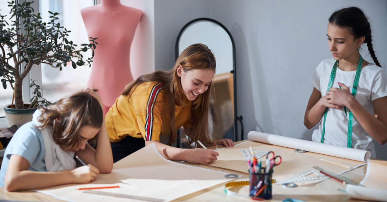 Cute girls drafting sewing patterns for dressmaking.