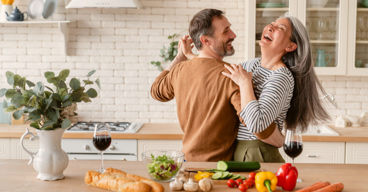 Happy couple dancing together in the kitchen while cooking.