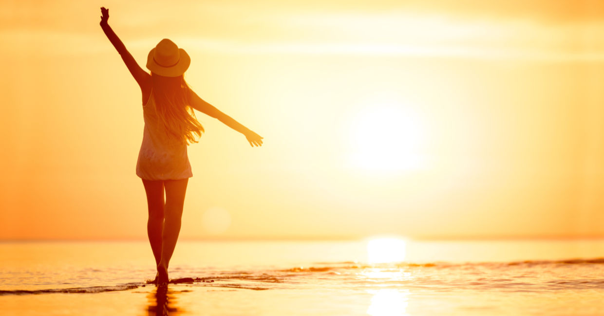 A woman enjoys a relaxing sunset stroll along the beach.