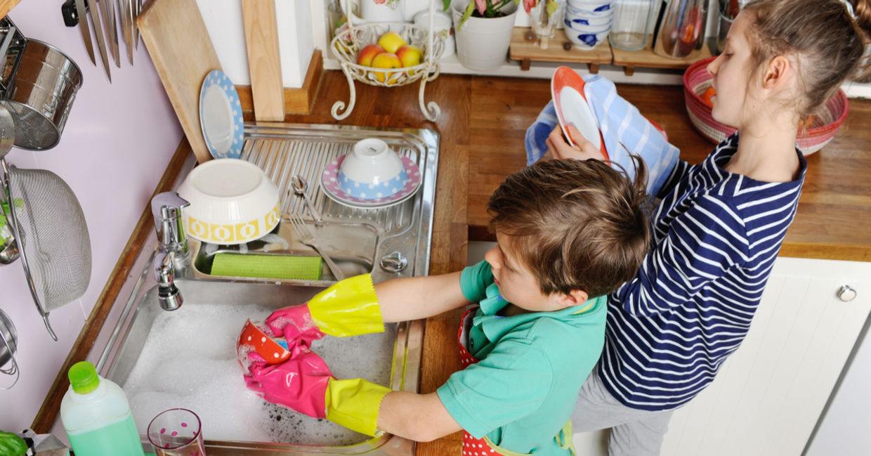 Two young children are washing dishes.