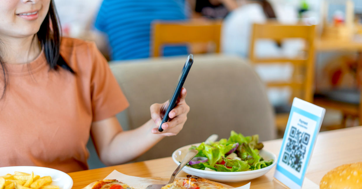 Woman using her smartphone to scan a food menu.
